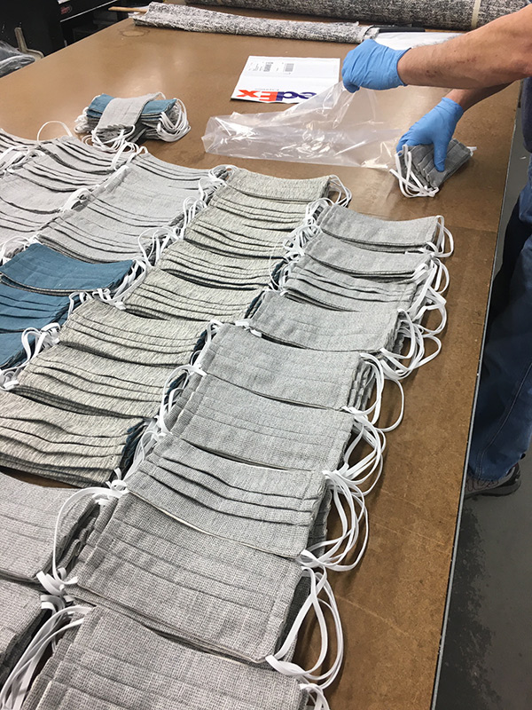 Workers packaging up reusable masks at Baker Furniture