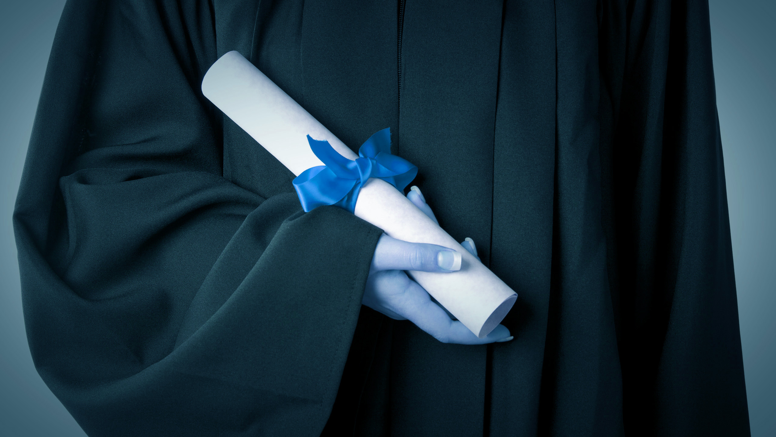 A woman holding a scrolled degree. The whole image has been tinted blue.