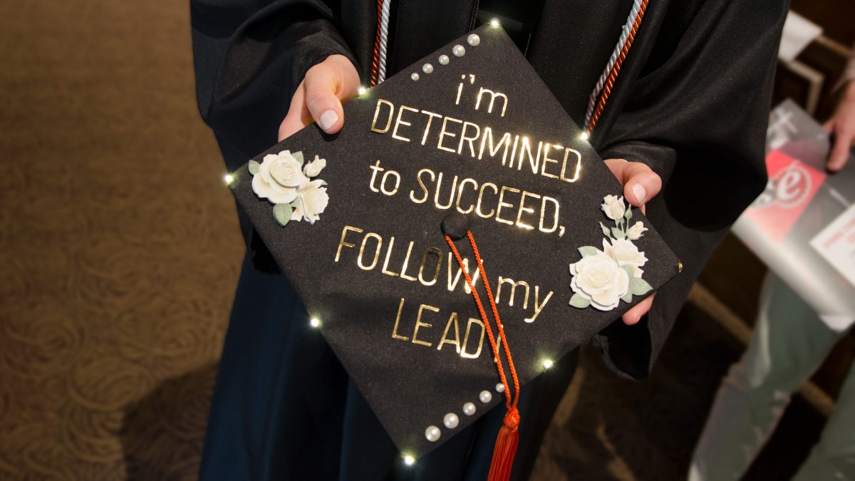 A close up of a student's cap. It says "I'm determined to succeed. Follow my lead".
