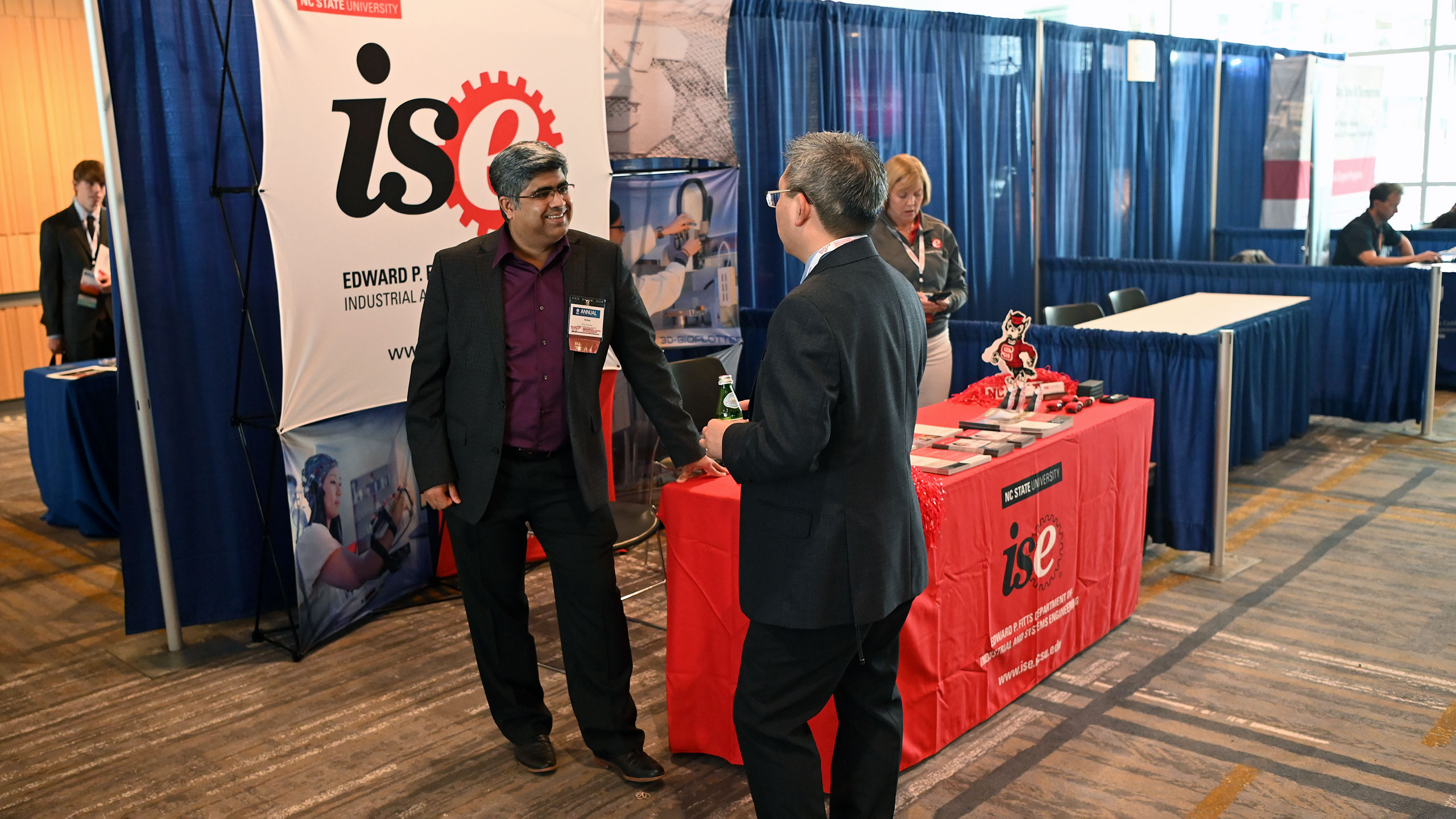Rohan Shirwaiker talking with a colleague at the ISE conference booth