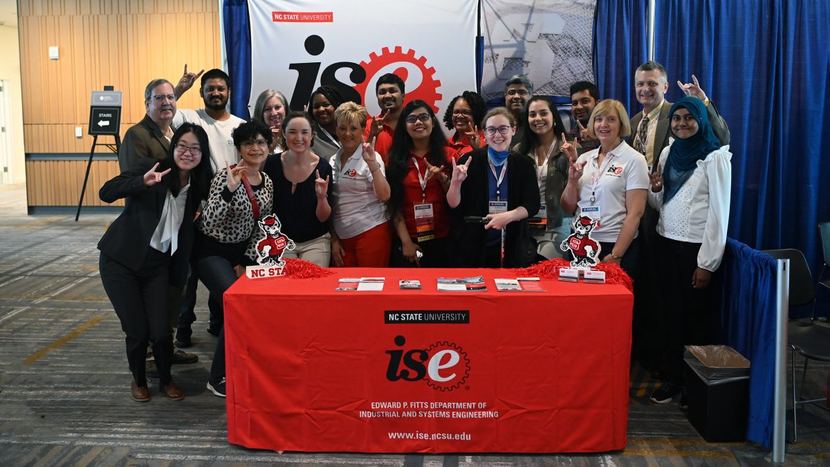 Faculty, staff and students gather around the ISE booth and flash their Wolfies.
