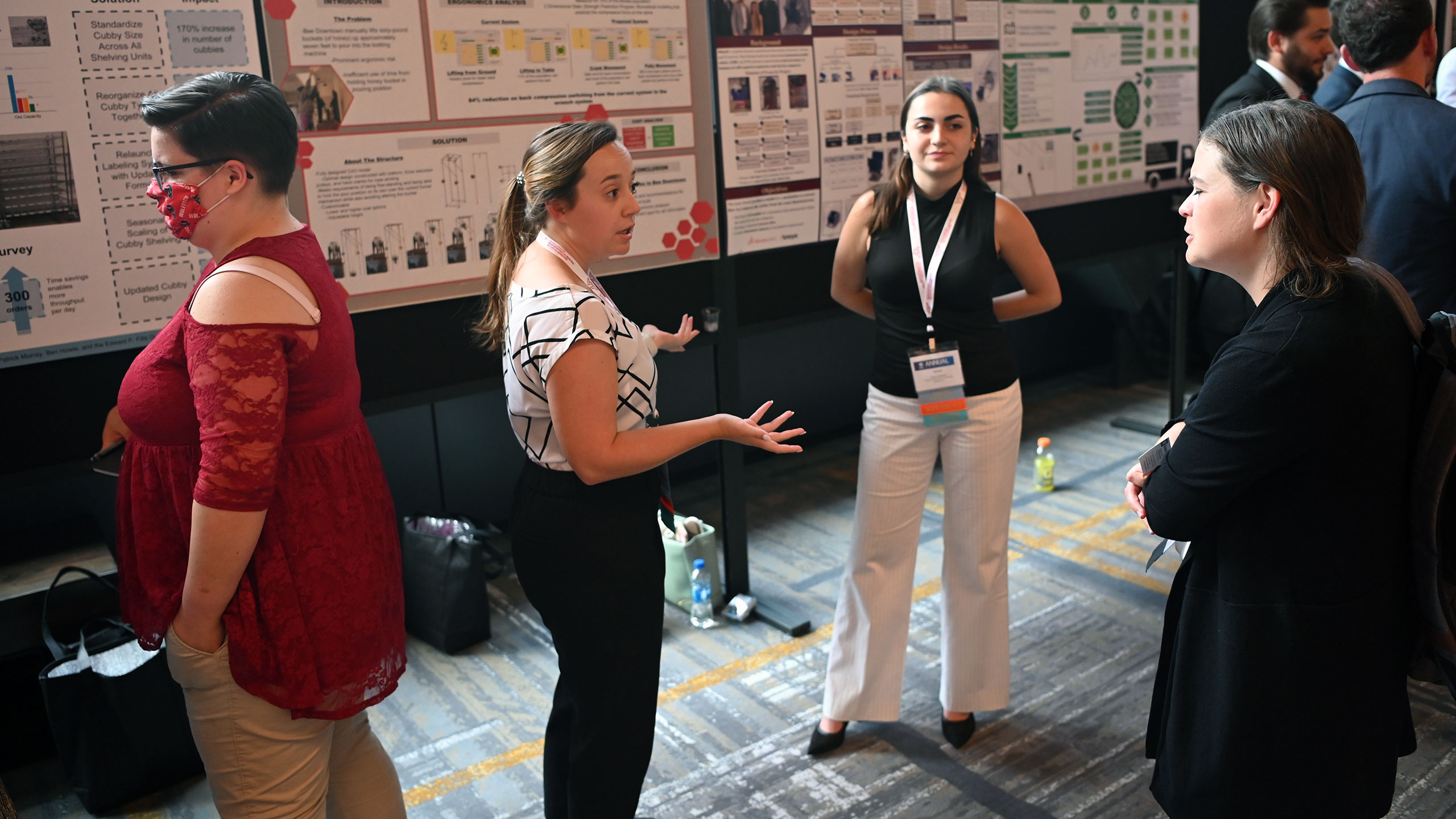 Rachel Boswell and Alyssa SaidiZand talking to a spectator in front of their research poster