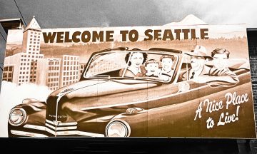 A billboard displaying a family of four riding in a convertible car with the slogan, "Welcome to Seattle"