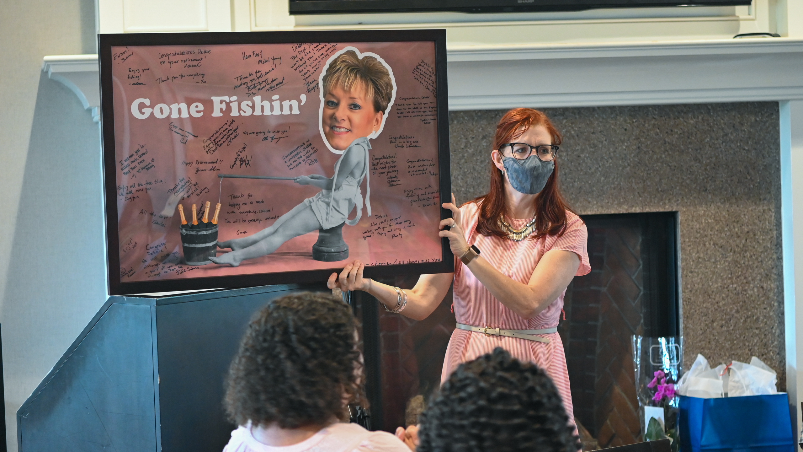 Julie Swann shows a goodbye poster that says Gone Fishin'. The poster is covered with signatures.