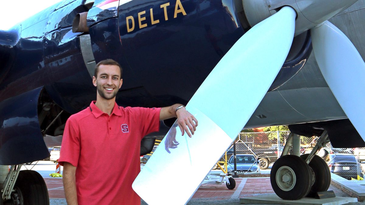 Ben Craver standing with his arm propped up on a planes propeller.