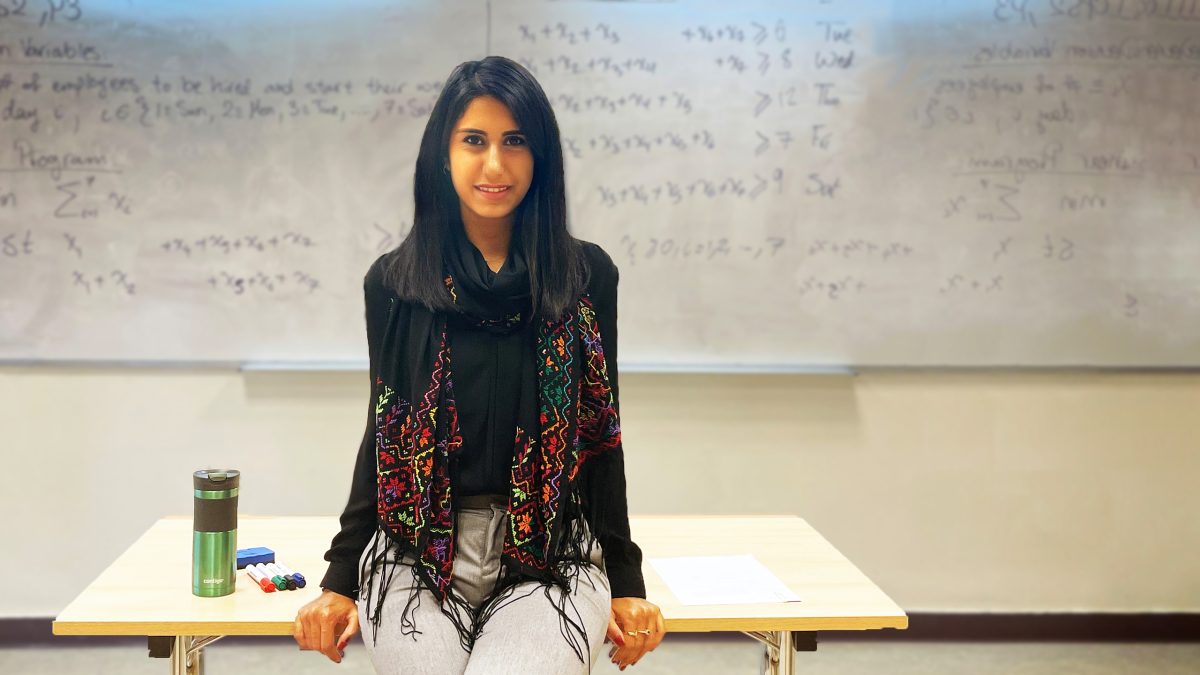 Photo of Lena Abu El Haija sitting on desk for Faces of ISE.