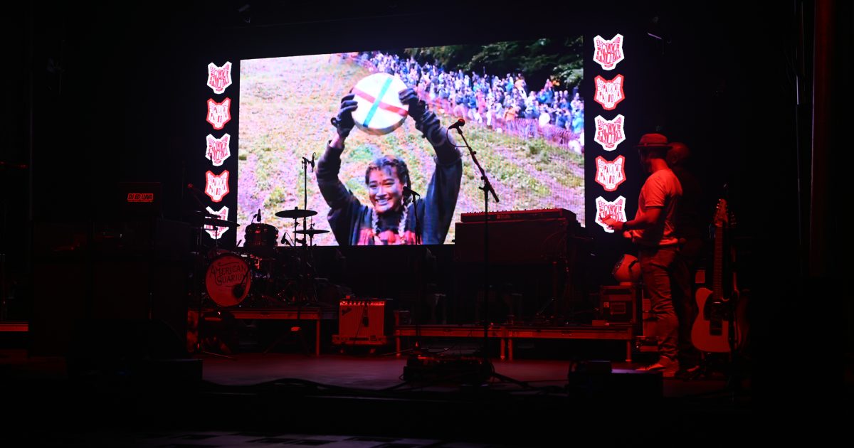 Video playing on stage of Abby at the cheese rolling event. 