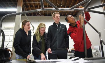 Mechanical engineering's Bryon Spells (right) points out recent welding work to SolarPack teammates while checking on the progress of their car at Eastern Rod and Customs.
