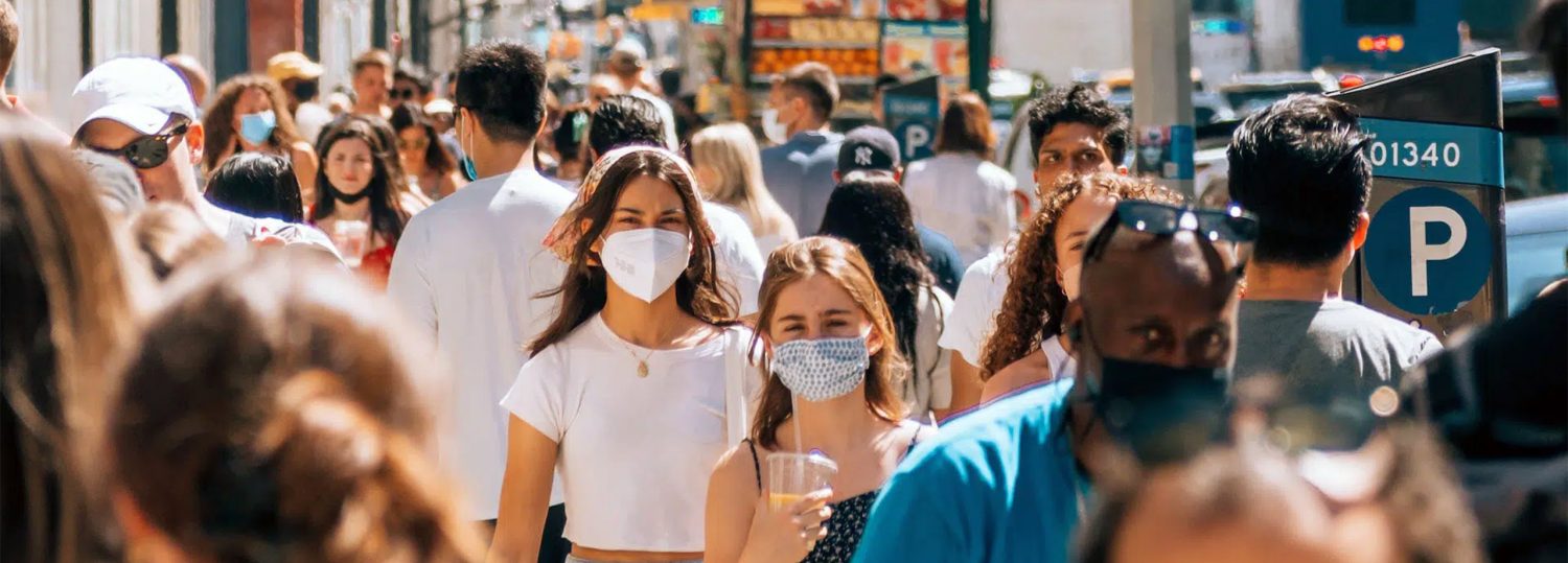 People wearing masks walking down a busy city street