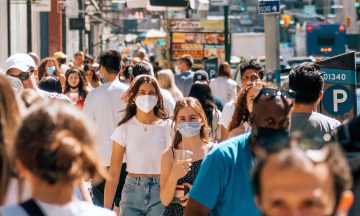People wearing masks walking down a busy city street