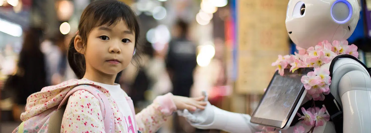 An Asian child holding the hand of a robot