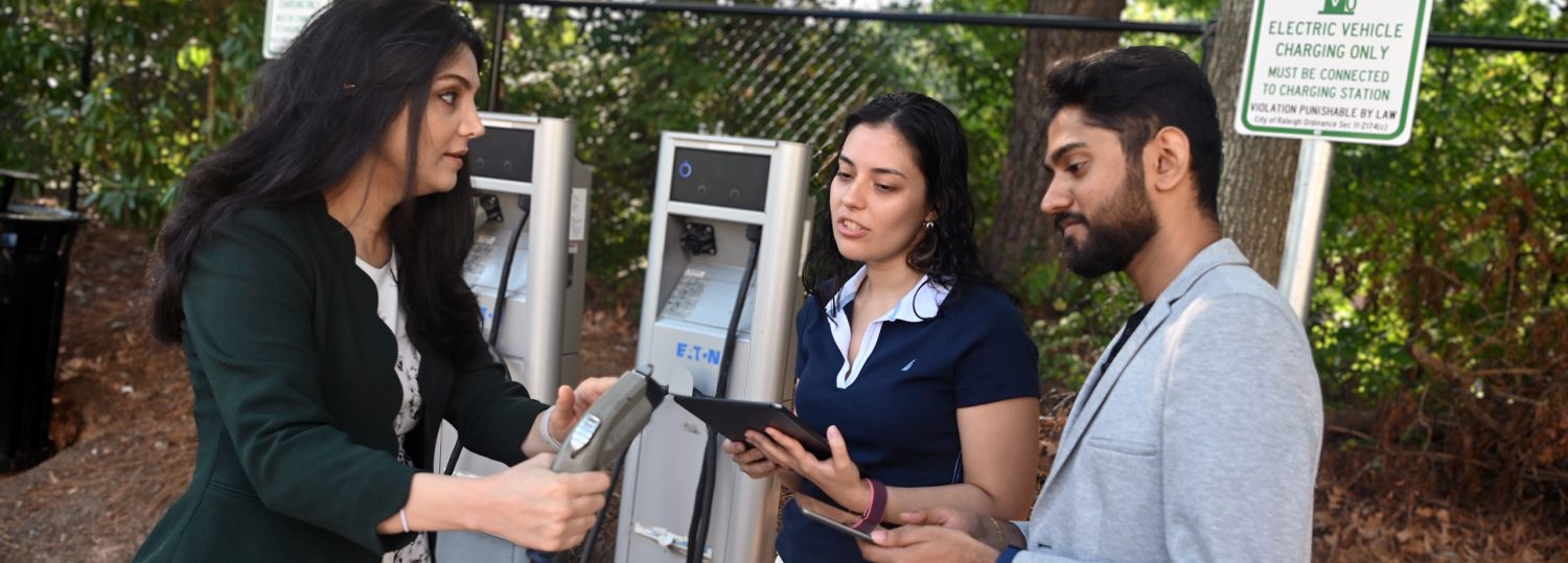 Leila Hajibabai working with two of her research students at an EV charging station