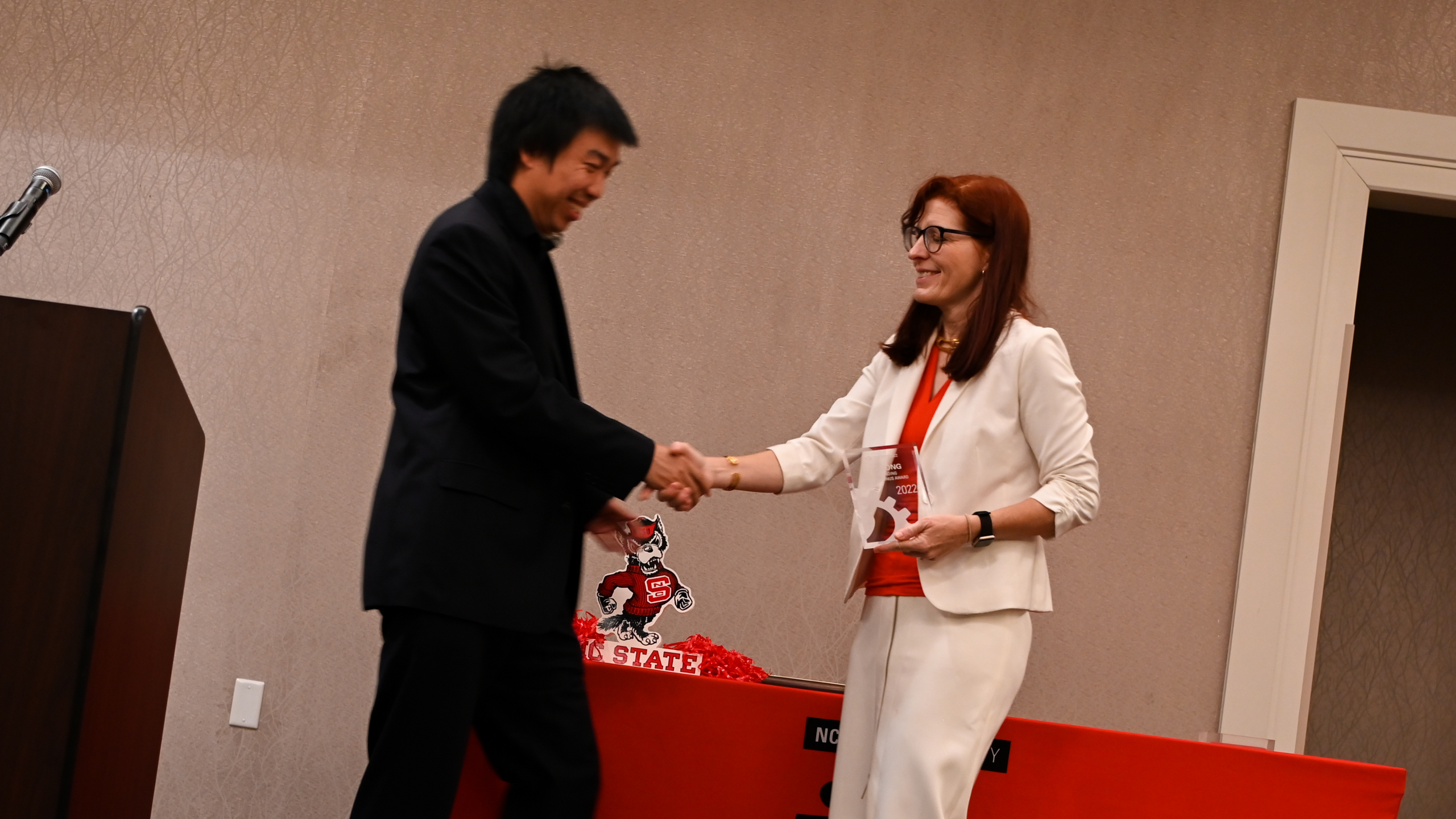 Outstanding Young Alumnus Dr. Tao Hong shaking hands with Dr. Julie Swann