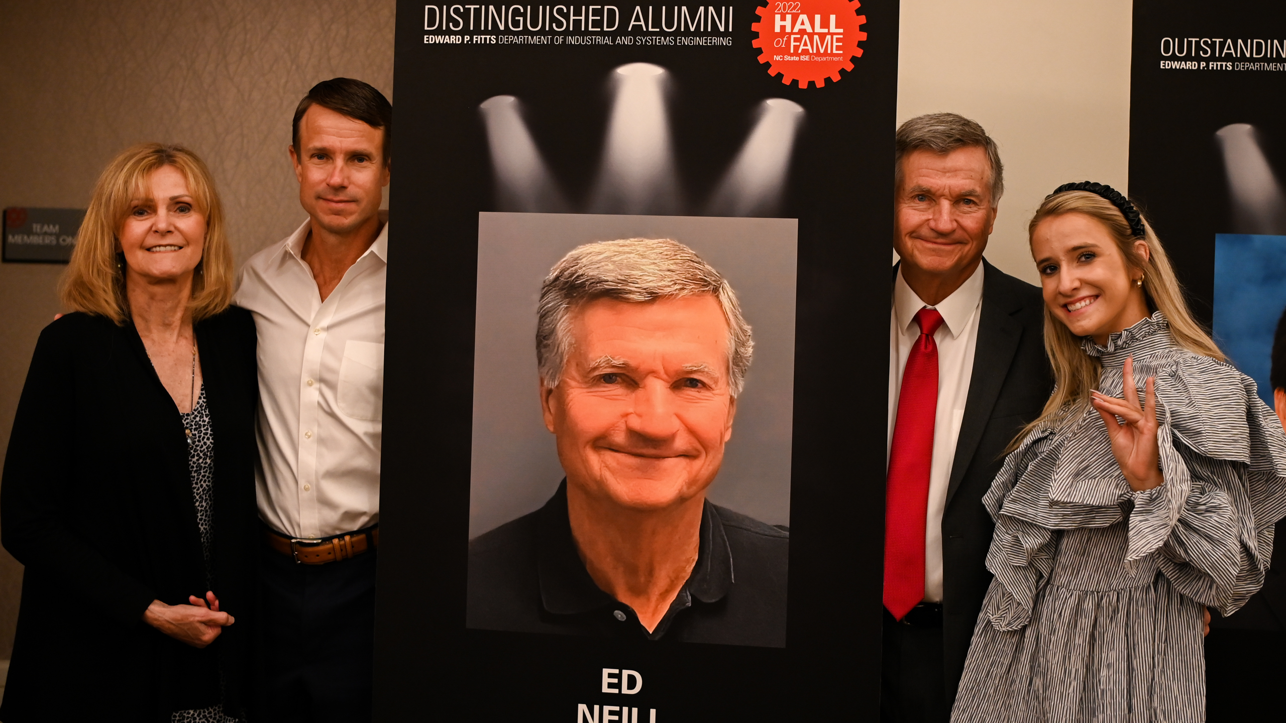 Ed Neill and his family posing in front of Ed's Distinguished Alumni banner