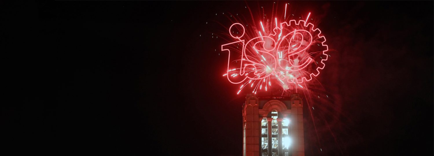 The NC State Belltower with the ISE logo exploding over bathing it in red light