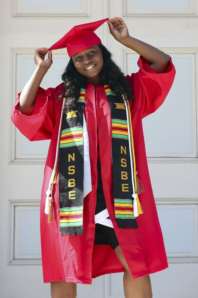Tabitha Gardner posing in her graduation cap and gown in front of the NC State Belltower.