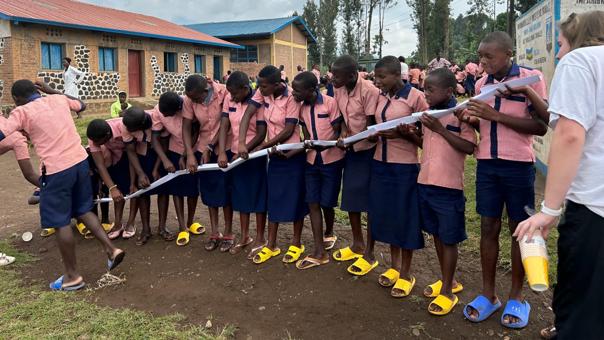  6th graders from Nkumba 1 primary school pictured working together as a team on the pipeline activity,  where they had to work together to get a ball into a cup 10 feet away only using their folded paper