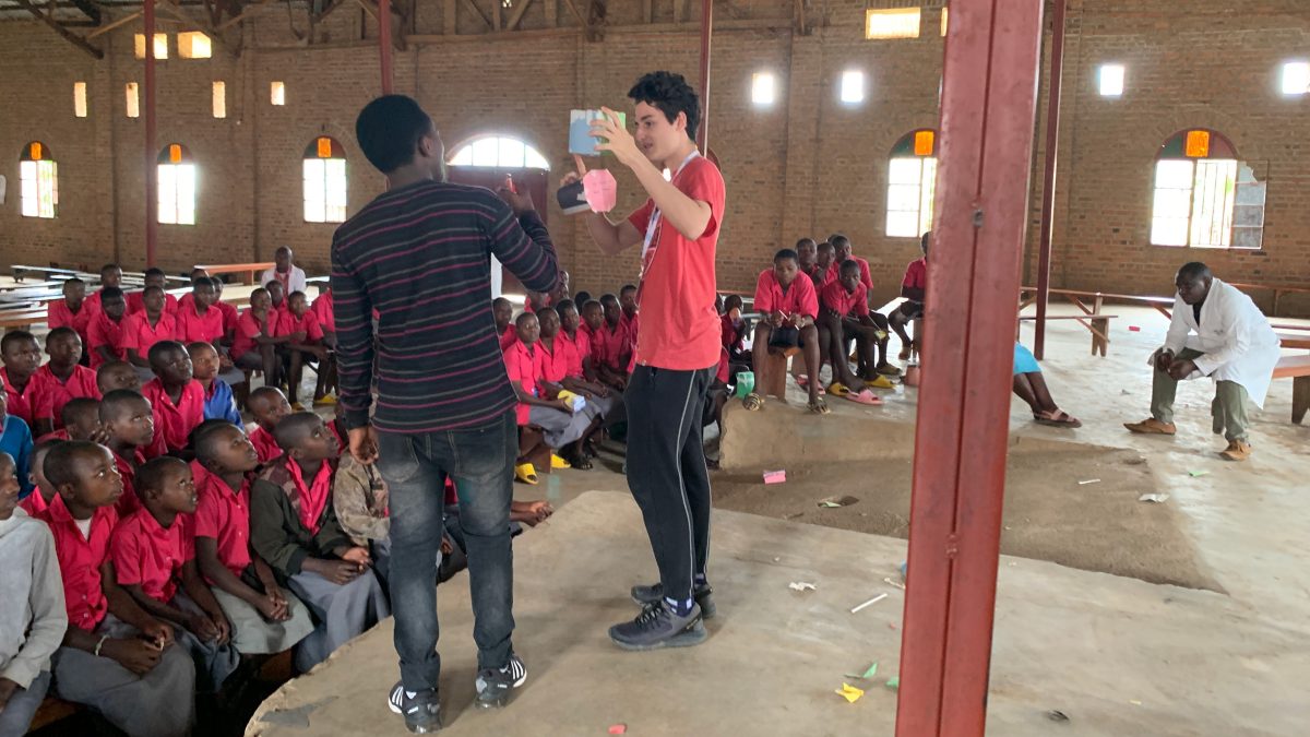 One of the team members was accompanied by a INES Ruhengeri (local Rwandan university student) that served as a translator. They are giving directions to the class on the paper house activity, where students had to build a house out of paper that could sustain weight.