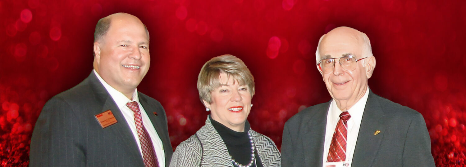 Dick Franklin, Wanda Franklin and Dick Bernhard standing in front of a red background