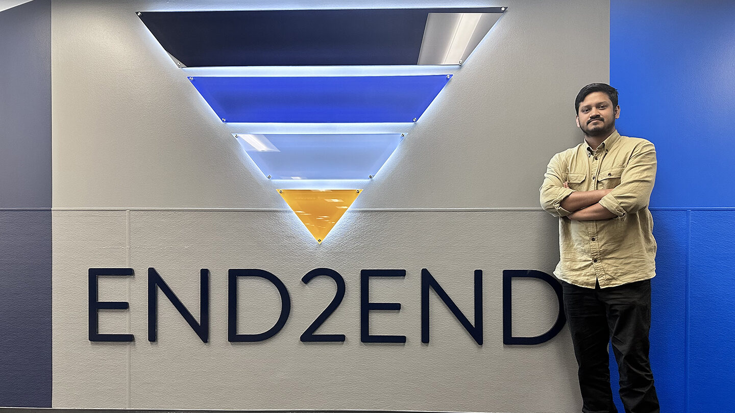 Tanzid Hasnain standing infront of his companies logo.