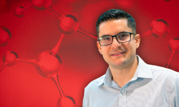 ISE associate professor Adolfo Escobedo standing in front of a red abstract background