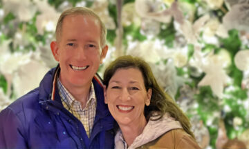 A headshot of Neil and Deanna Brittain standing in front of a Christmas lights