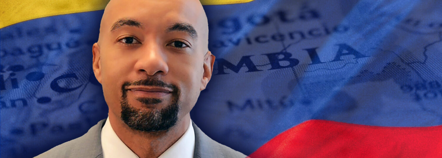 A headshot of Kanton Reynolds standing in front of a Colombian flag